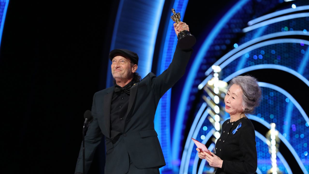 Troy Kotsur, left, accepts the actor in a supporting role award for "CODA" from Youn Yuh-jung onstage during the 94th Annual Academy Awards.