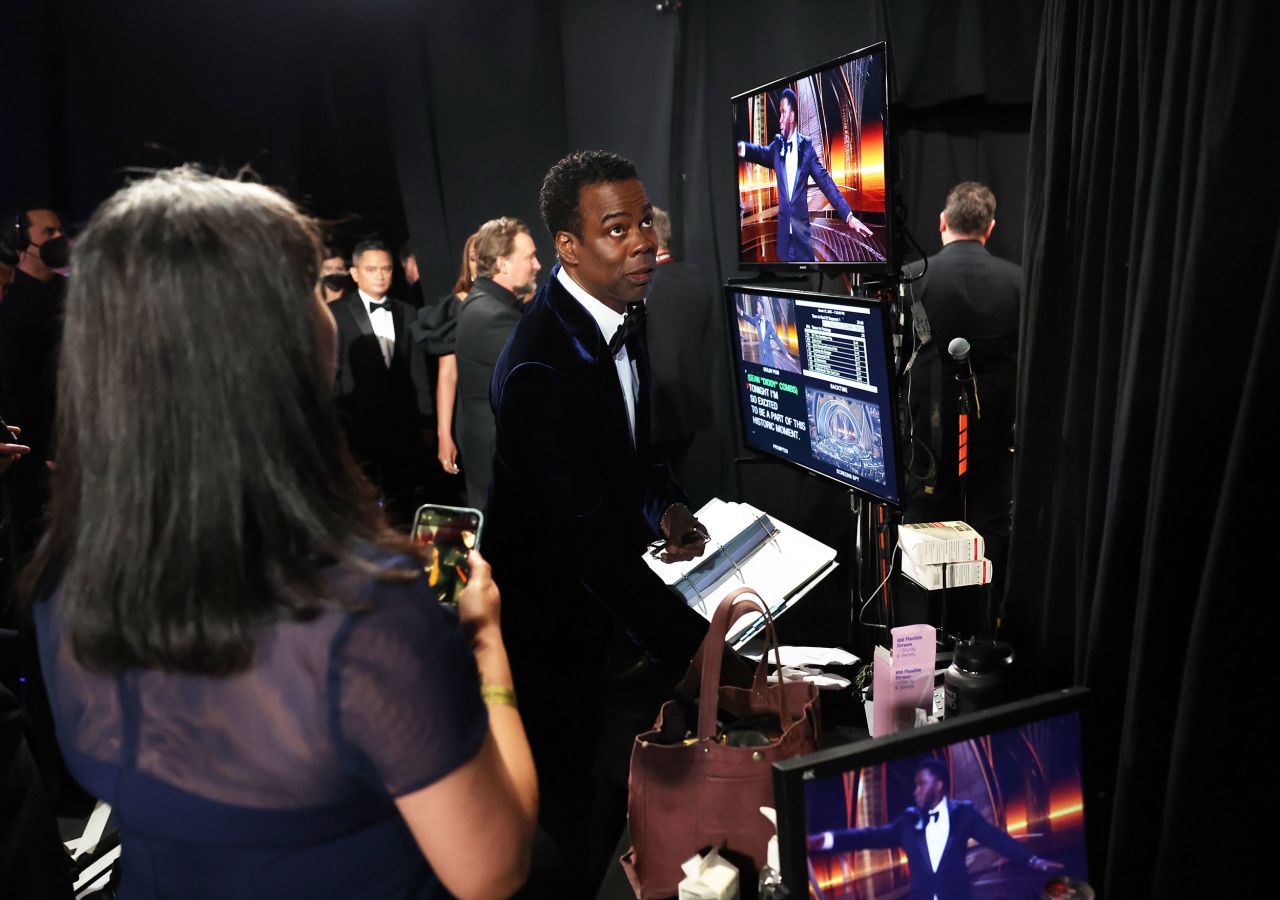 Chris Rock, backstage, watches Sean "Diddy" Combs on a monitor. Combs told the audience Smith and Rock would settle things "like family" later.