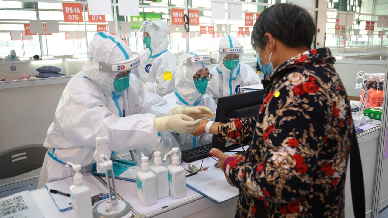 Staff members help a patient to register at a designated quarantine facility in Shanghai on March 26.
