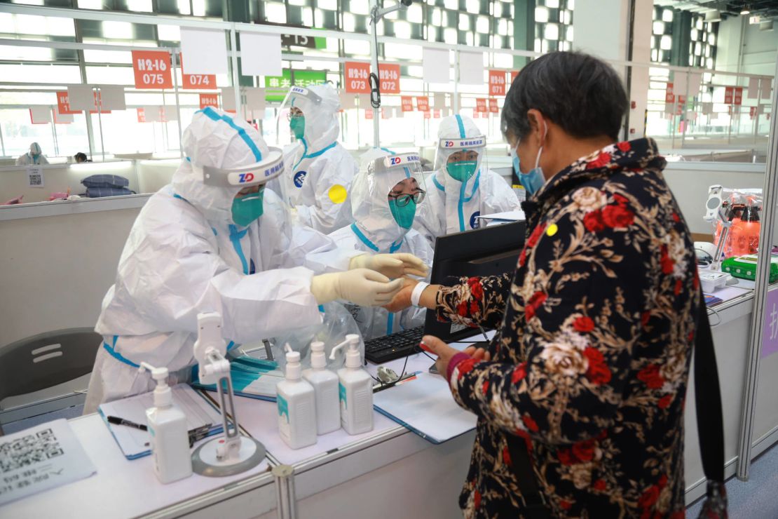 Staff members help a patient to register at a designated quarantine facility in Shanghai on March 26.
