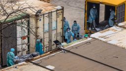 Workers move the bodies of deceased people from a truck into a refrigerated container at the Fu Shan Public Mortuary in Hong Kong on March 16, 2022, amid the city's worst-ever Covid-19 coronavirus outbreak that has seen overflowing hospitals and morgues and a frantic expansion of the city's spartan quarantine camp system. 