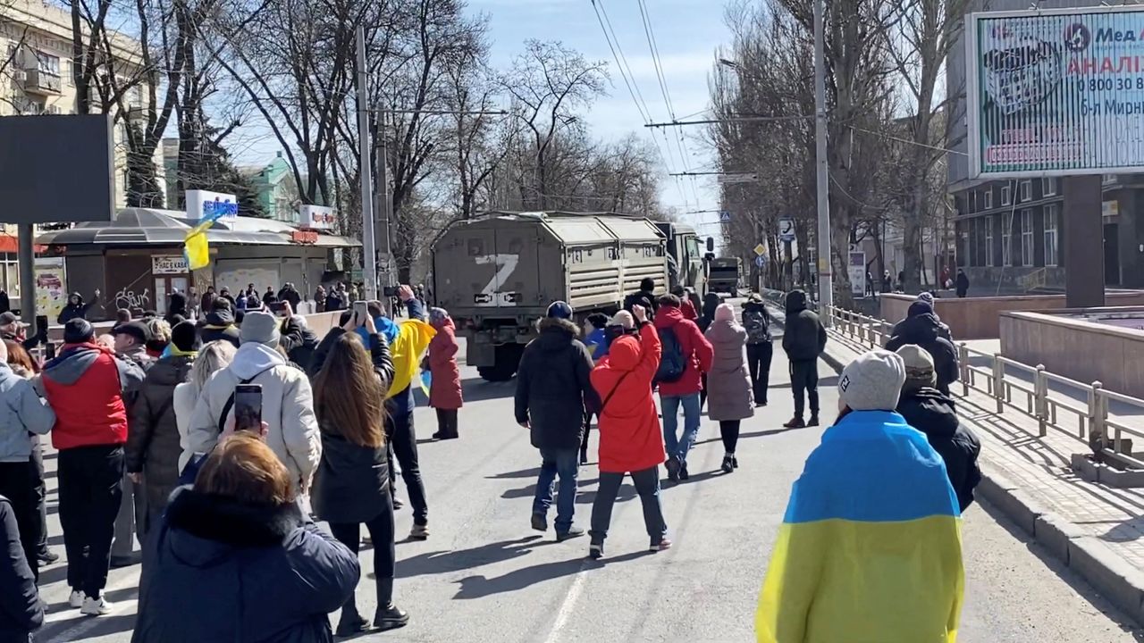 Demonstrators chant "go home" while Russian military vehicles reverse course on a road in Kherson on March 20.