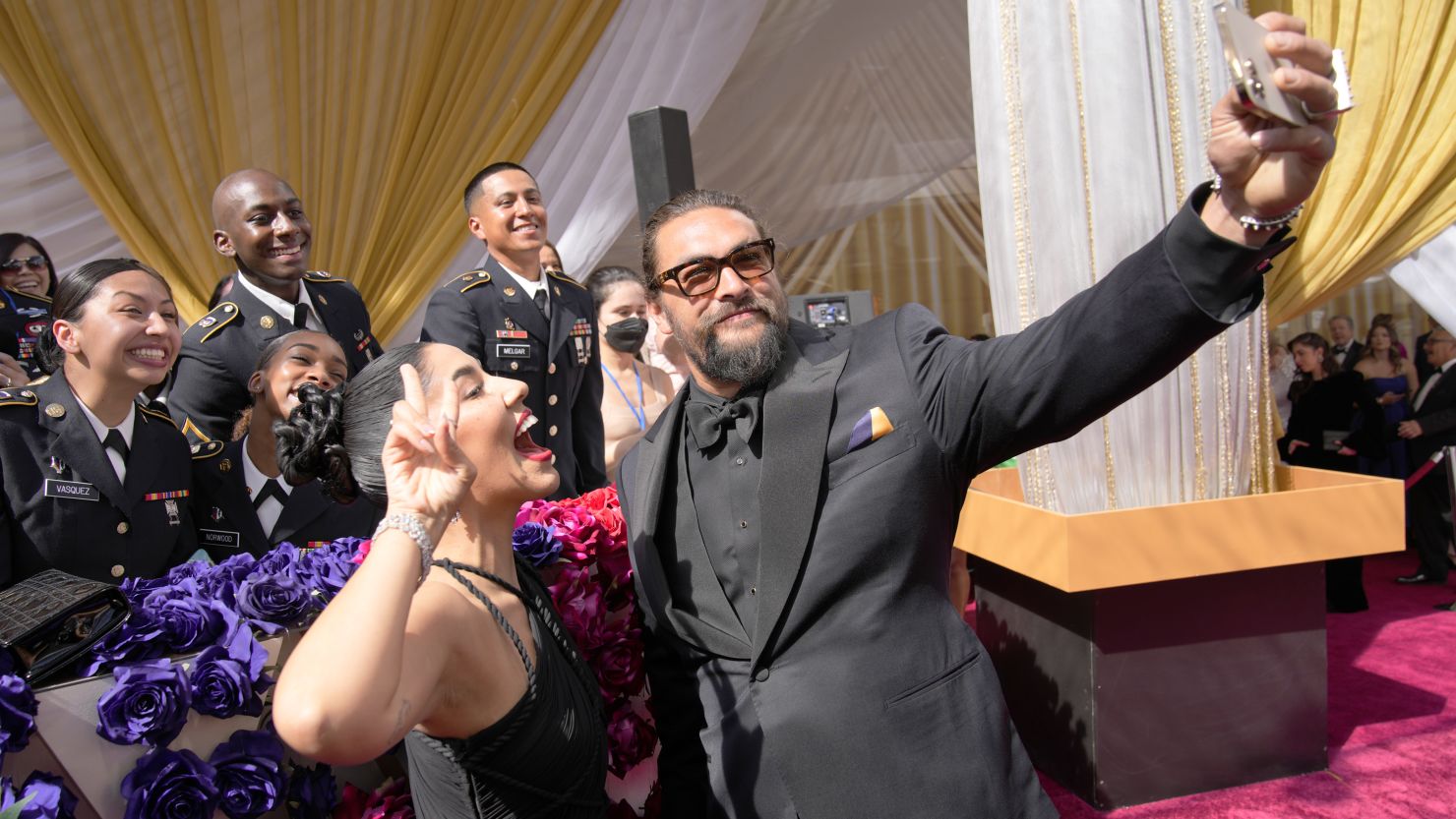 Stephanie Beatriz, left, and Jason Momoa take a photograph with members of the military at the Oscars on Sunday,