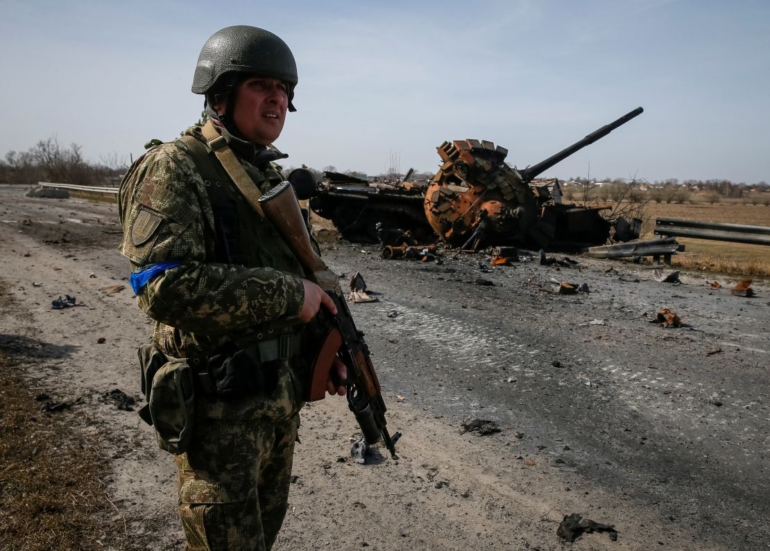 A Ukrainian serviceman stands near the wreck of a Russian tank on the front lines in the Kyiv region, Ukraine on March 28.