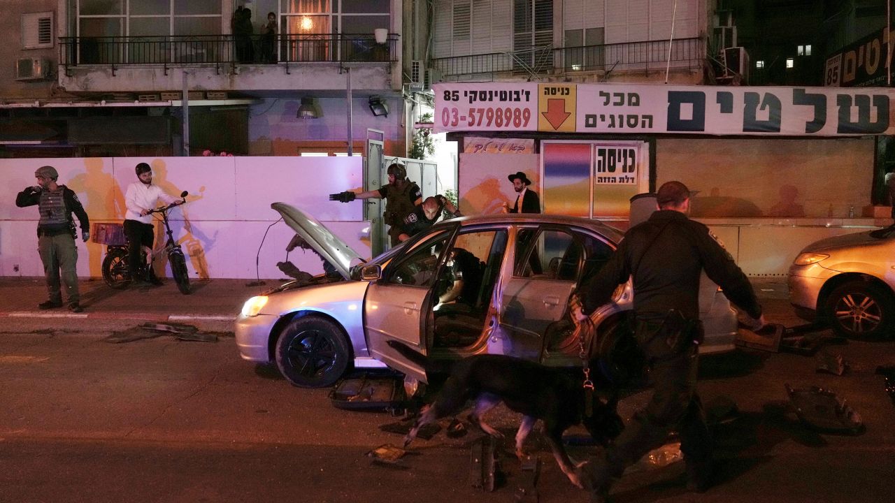Israeli police search a car at the scene of a shooting in Bnei Brak on Tuesday.