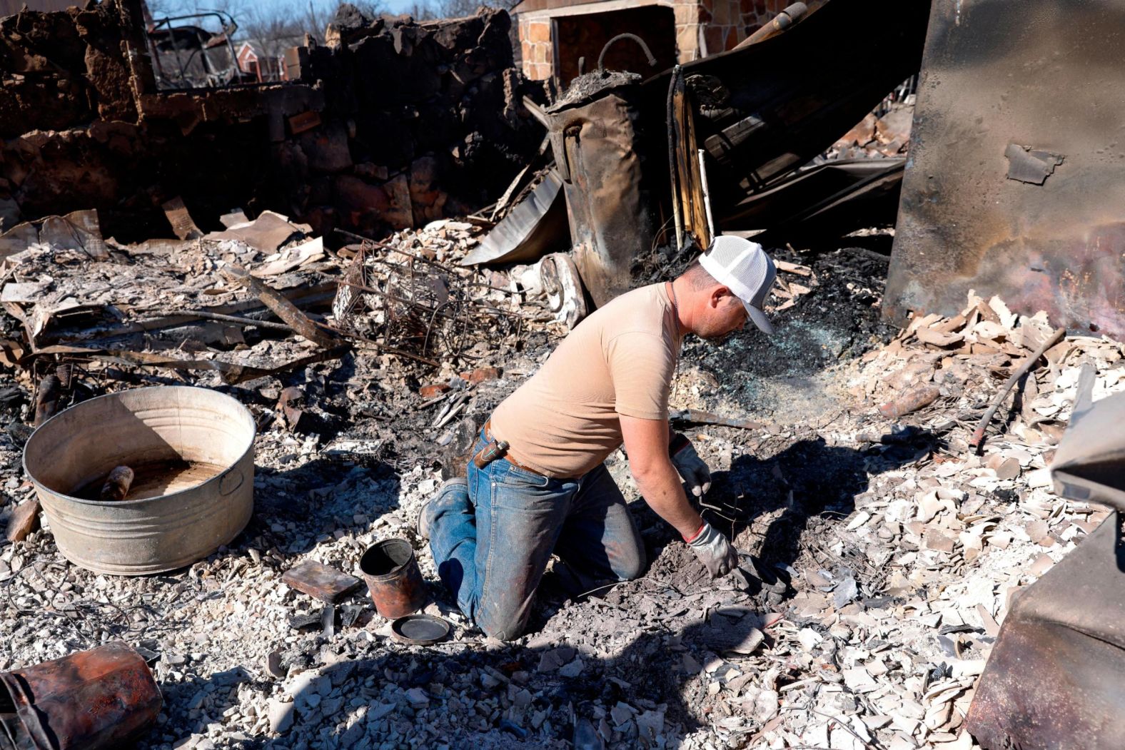 Seth Griffin sorts through the ashes of his mother's home in Carbon, Texas, on March 19. He was searching for coins they collected together.