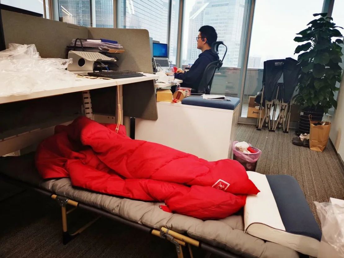A camping bed set up under at an employee's desk at a company in Shanghai.
