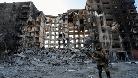 A service member of pro-Russian troops walks near a destroyed apartment building in the besieged port city of Mariupol on March 28, 2022.