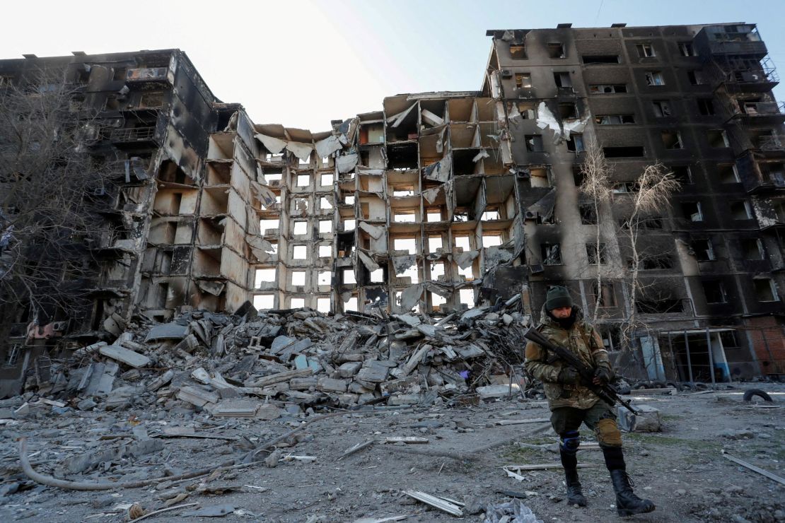 A service member of pro-Russian troops walks near a destroyed apartment building destroyed in the besieged southern port city of Mariupol on March 28, 2022.