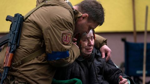 A soldier comforts 82-year-old Larysa Kolesnyk after she was evacuated from Irpin, on the outskirts of kyiv, on March 30, 2022.