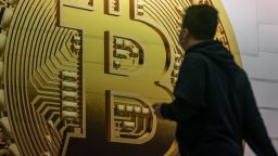 Pedestrians walk past an advertisement displaying a Bitcoin cryptocurrency token on February 15, 2022 in Hong Kong, China.