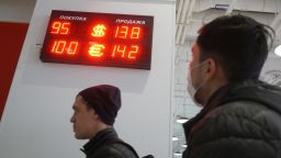 MOSCOW, RUSSIA - MARCH 7: (RUSSIA OUT) People walk nearby the Fora bank branch with a screen showing the currency exchange rates of U.S. Dollar and Euro to Russian Ruble, on March 7, 2022 in Moscow, Russia. Western brands, such as Puma, Bershka, Pull&Bear, IKEA and H&M closed their stores in Russia this week as a result of the U.S. and EU economic sanctions. (Photo by Konstantin Zavrazhin/Getty Images)