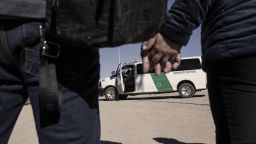 Migrants seeking asylum hold hands as they walk towards a U.S. Customs and Border Protection vehicle to be transferred to temporary shelter in Yuma, Arizona, U.S., on Friday, Feb. 18, 2022.