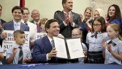 Florida Gov. Ron DeSantis displays the signed Parental Rights in Education, aka the Don't Say Gay bill, flanked by elementary school students during a news conference on Monday, March 28, 2022, at Classical Preparatory school in Shady Hills. (Douglas R. Clifford/Tampa Bay Times via AP)