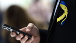 A man sporting a ribbon with colors of the Ukrainian flag uses a smartphone in Barcelona on March 1, 2022. 