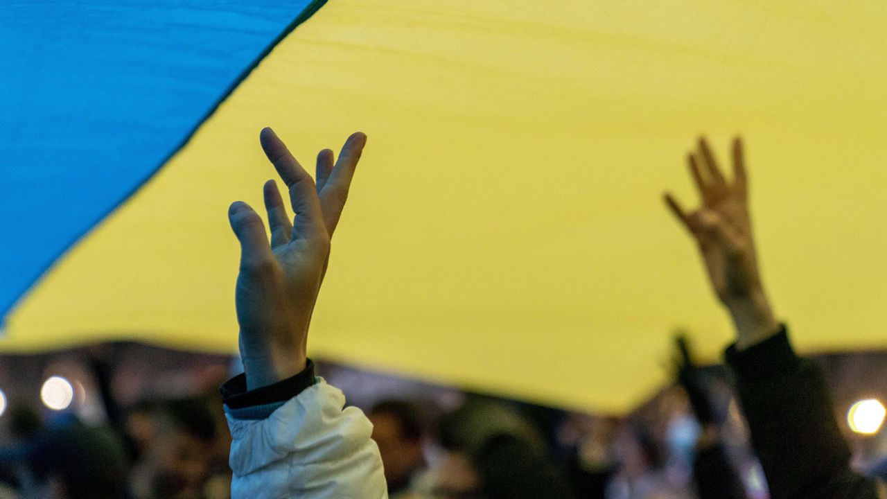 People stand under a giant Ukrainian flag during a vigil to protest the Russian invasion of Ukraine in front of the White House on Feb. 24.