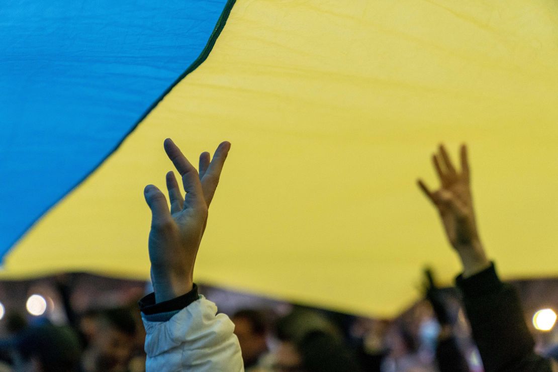 People stand under a giant Ukrainian flag during a vigil to protest the Russian invasion of Ukraine in front of the White House on Feb. 24.