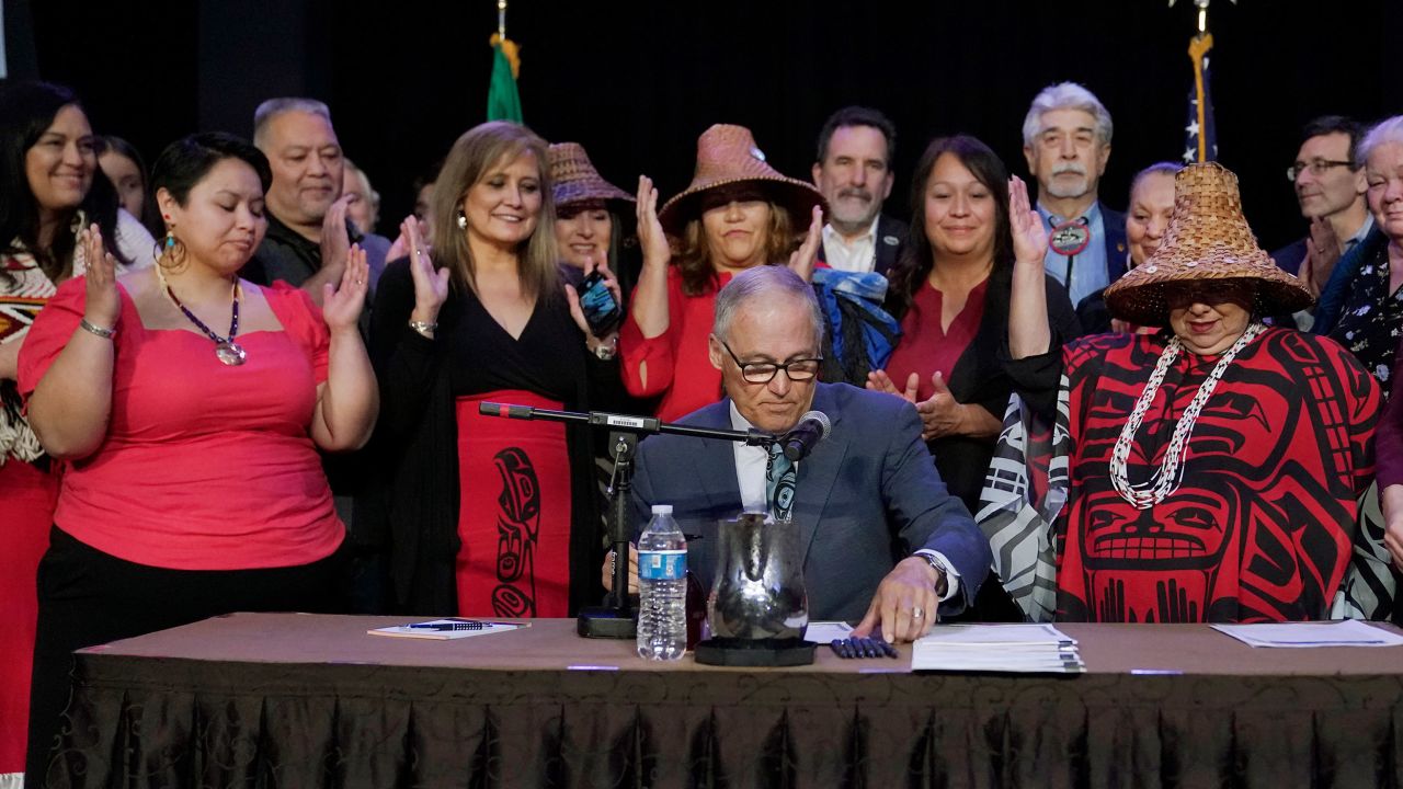 Washington Gov. Jay Inslee, center, signs a bill on Thursday that creates a first statewide alert system for missing Indigenous people.
