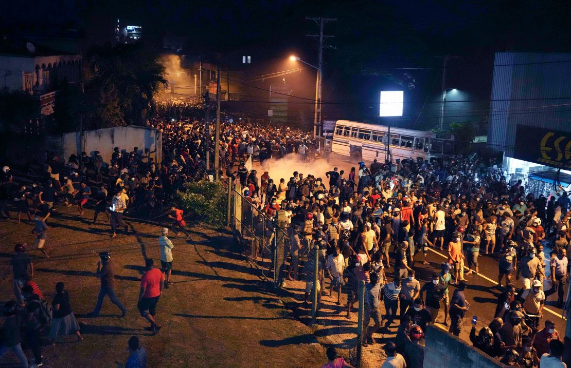 Protesters run to take cover as police use tear gas during a protest outside the Sri Lankan President's house on  March 31, 2022. 