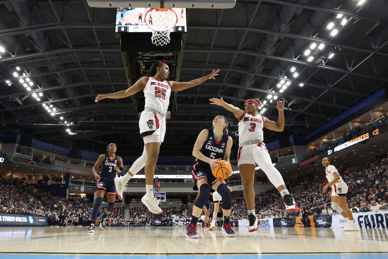 UConn star Paige Bueckers is defended by NC State's Kayla Jones, left, and Kai Crutchfield during an NCAA Tournament game on Monday, March 28. Bueckers scored 27 points as UConn won in double overtime and booked a spot in the Final Four. The Huskies have now made 14 Final Fours in a row.