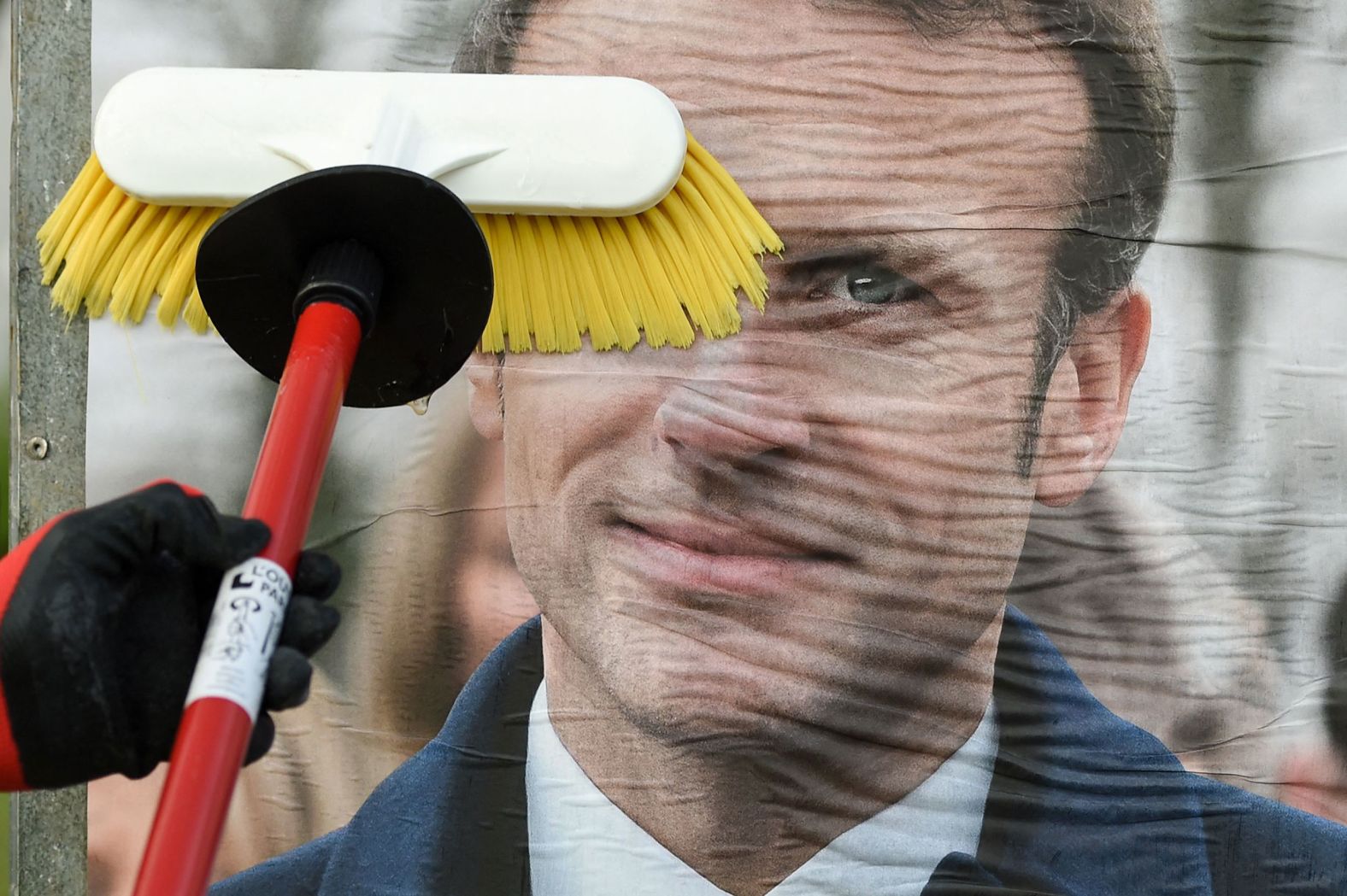 A worker in Saint-Herblain, France, smooths out a campaign poster of French President Emmanuel Macron on Monday, March 28. <a href="index.php?page=&url=https%3A%2F%2Fwww.cnn.com%2F2022%2F03%2F03%2Feurope%2Ffrance-politics-second-term-bid-president-intl%2Findex.html" target="_blank">Macron is seeking a second term in office.</a>