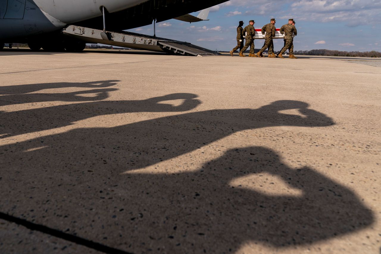 The shadows of saluting military members are seen as a US Marine carry team moves the transfer case of Gunnery Sgt. James W. Speedy at Dover Air Force Base in Delaware on Friday, March 23. Speedy, 30, was one of <a href="https://www.cnn.com/2022/03/20/politics/us-marines-norway/index.html" target="_blank">four Marines who died during a training flight in Norway</a> on March 18.