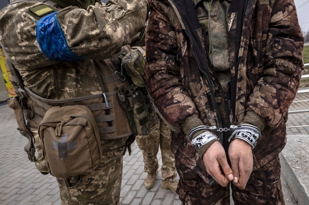 A Ukrainian serviceman stands with a handcuffed Russian soldier in Kharkiv on March 31.