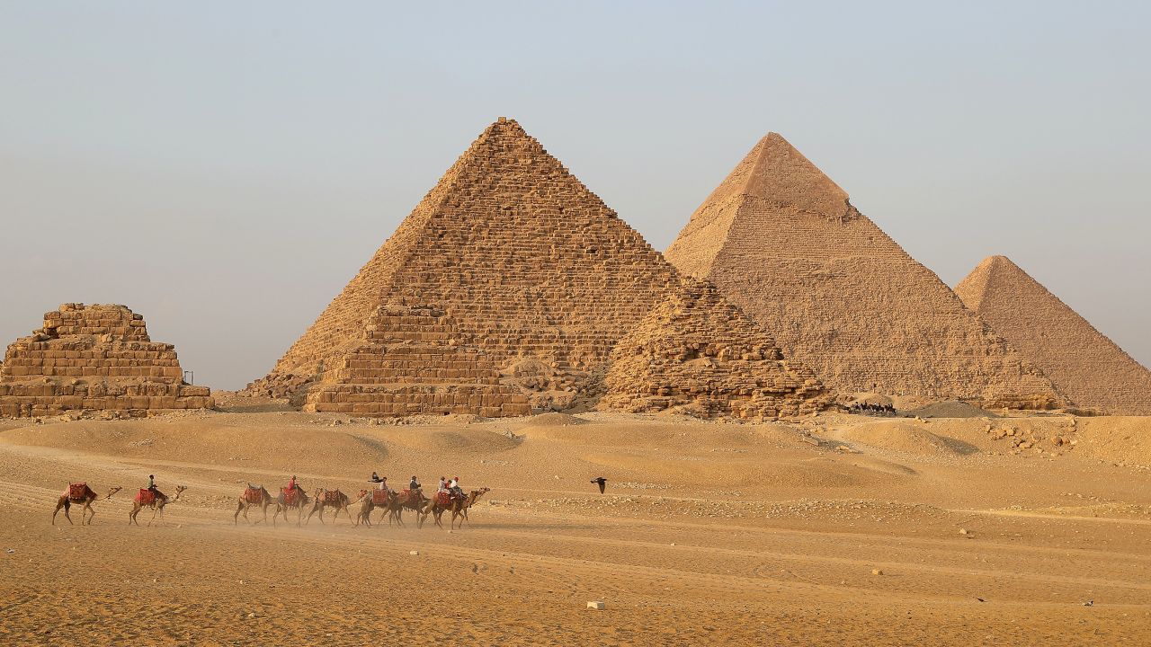 Tourists ride camels to view the Giza Pyramids in Giza, Egypt, on Oct. 21, 2021.