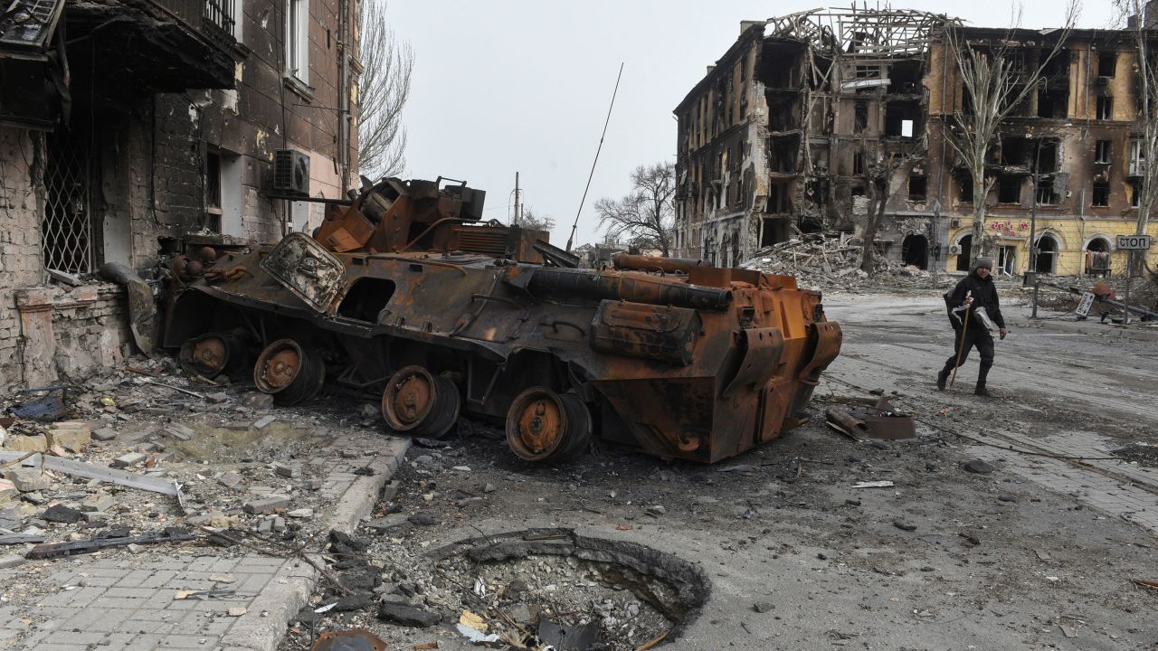 A man walks past a burnt armoured personnel carrier near buildings destroyed in the course of Ukraine-Russia conflict in the southern port city of Mariupol, Ukraine April 1, 2022. REUTERS/Stringer
