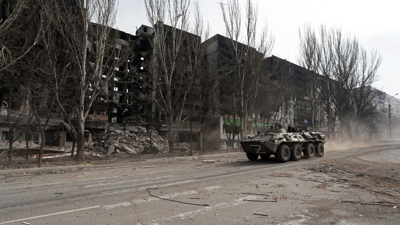 A armored vehicle with pro-Russian troops drives along a street past a residential building destroyed in the besieged southern port city of Mariupol, on March 31, 2022.