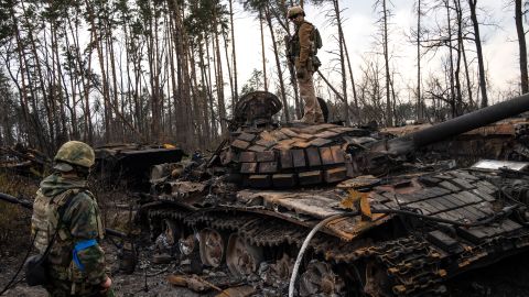 A Ukrainian soldier stands on top of a destroyed Russian tank on the outskirts of Kyiv on March 31, 2022.