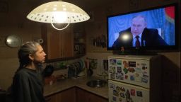 A woman watches TV with Russian President Putin speaking during a broadcast of a meeting of the National Security Council on the recognition of the self-proclaimed Donetsk People's Republic (DPR) and the Luhansk People's Republic (LPR), in St. Petersburg, Russia, 21 February 2022. 