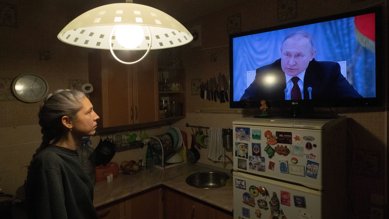 A woman watches Putin speaking during a TV broadcast of a meeting of the National Security Council on the recognition of the self-proclaimed Donetsk People's Republic and the Luhansk People's Republic on February 21, 2022. 