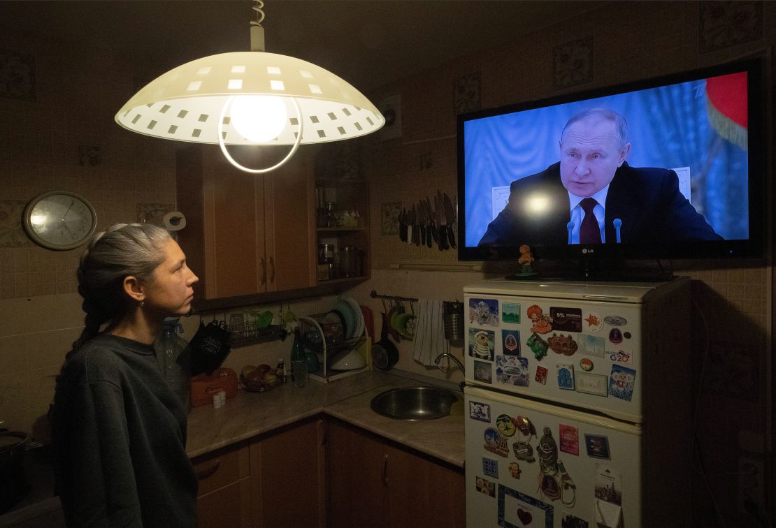 A woman watches Putin speaking during a TV broadcast of a meeting of the National Security Council on the recognition of the self-proclaimed Donetsk People's Republic and the Luhansk People's Republic on February 21, 2022. 