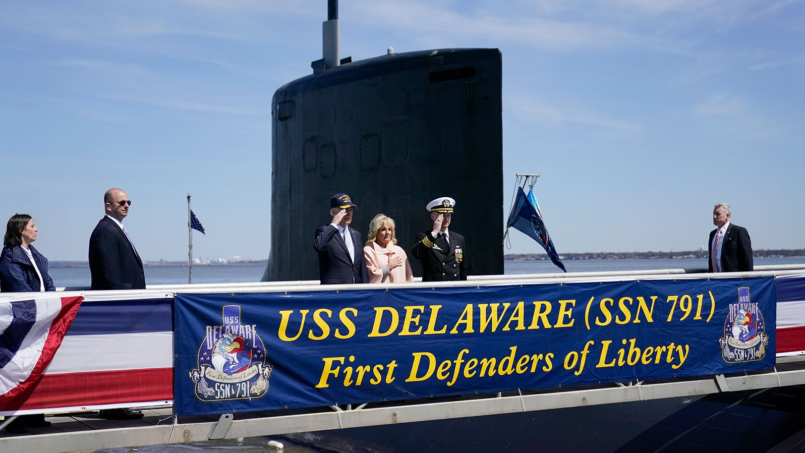 President Joe Biden returns a salute on April 2, 2022, as he stands with first lady Jill Biden and Cmdr. Matthew Horton before they board the USS Delaware for a tour in Wilmington, Delaware.