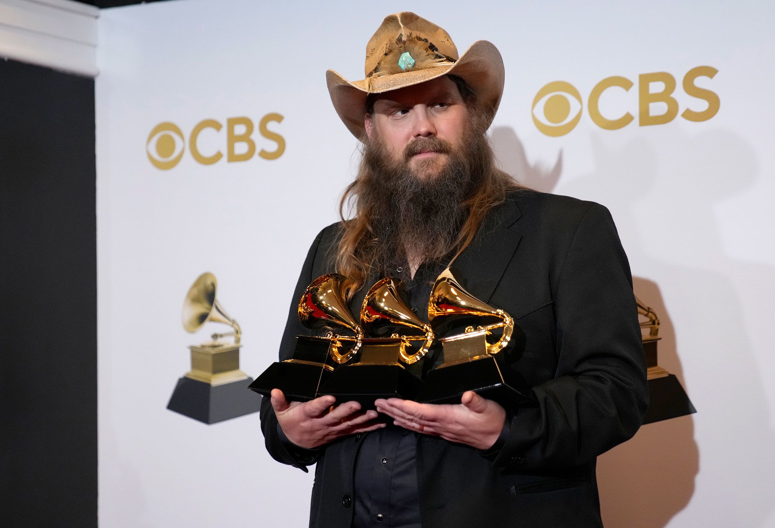 Chris Stapleton holds several of his Grammys in the press room.