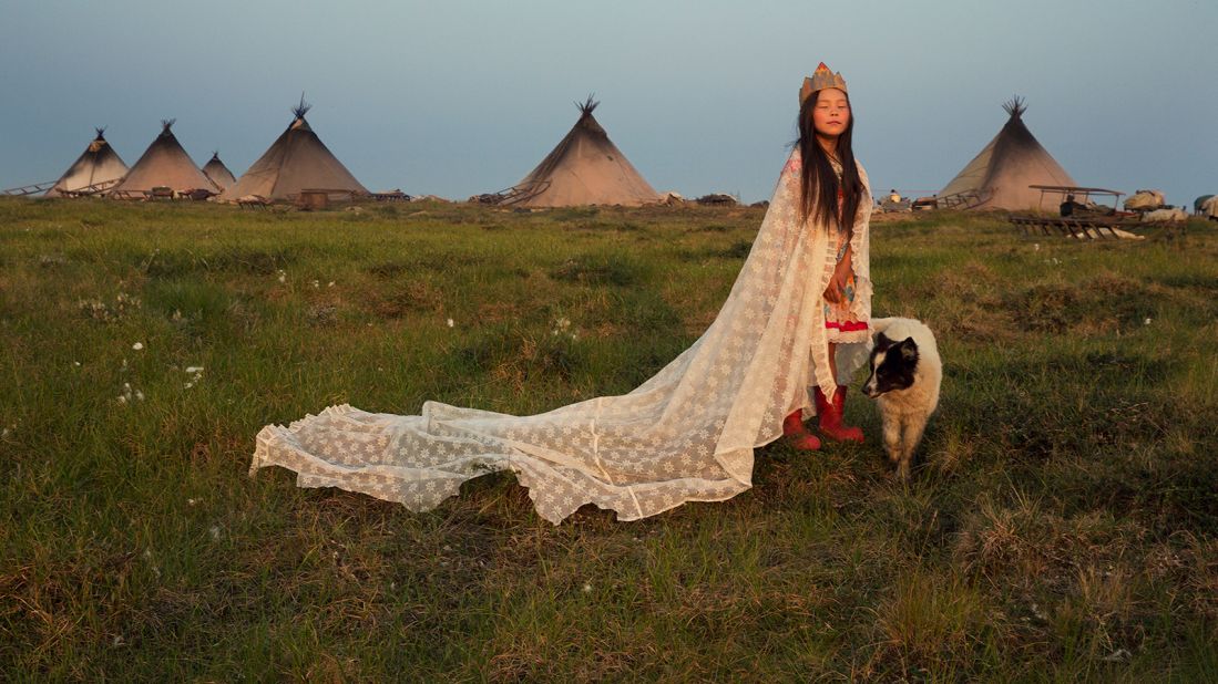 Christina is dressed up in a curtain and a crown made of a carton box. She poses as the Princess of Tundra in the Nenets reindeer herders' camp, in this photo take by Evgenia Arbugaeva.