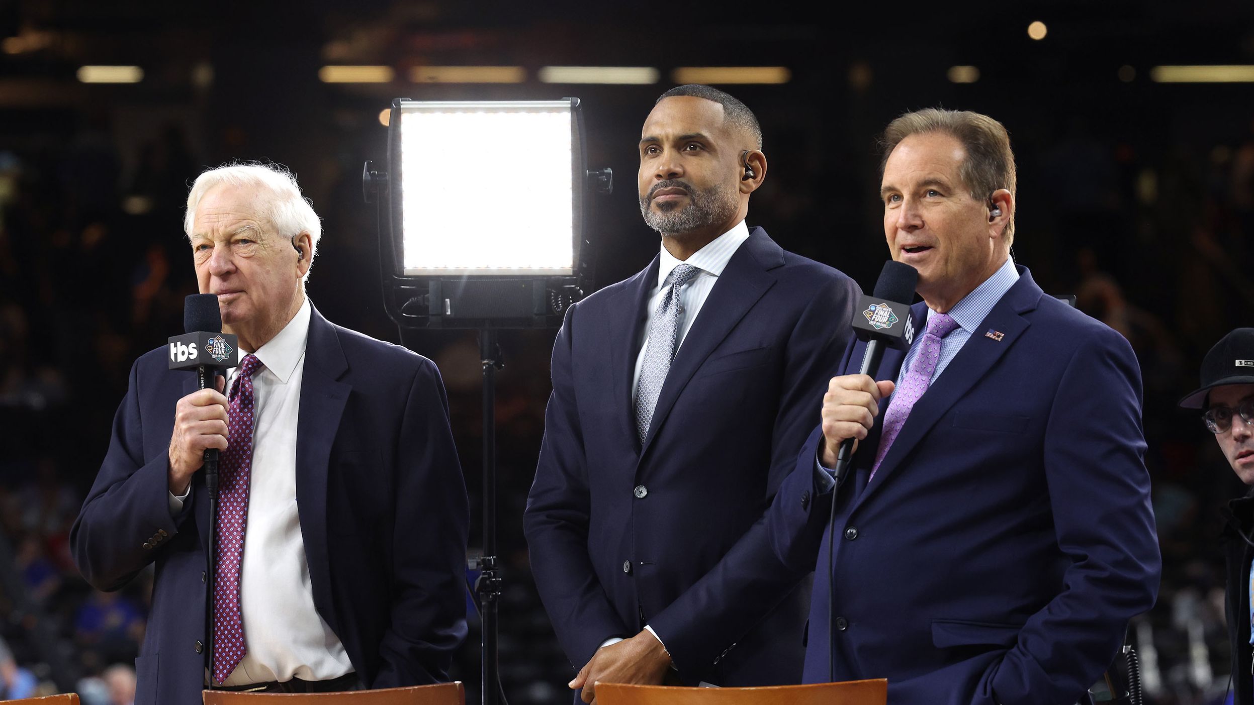 From left, TV announcers Bill Raftery, Grant Hill and Jim Nantz stand on the sidelines.