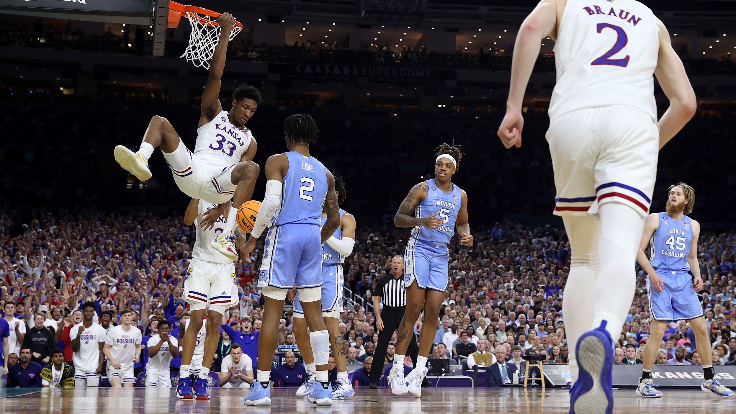 Kansas' David McCormack hangs from the basket after a dunk to start the second half.