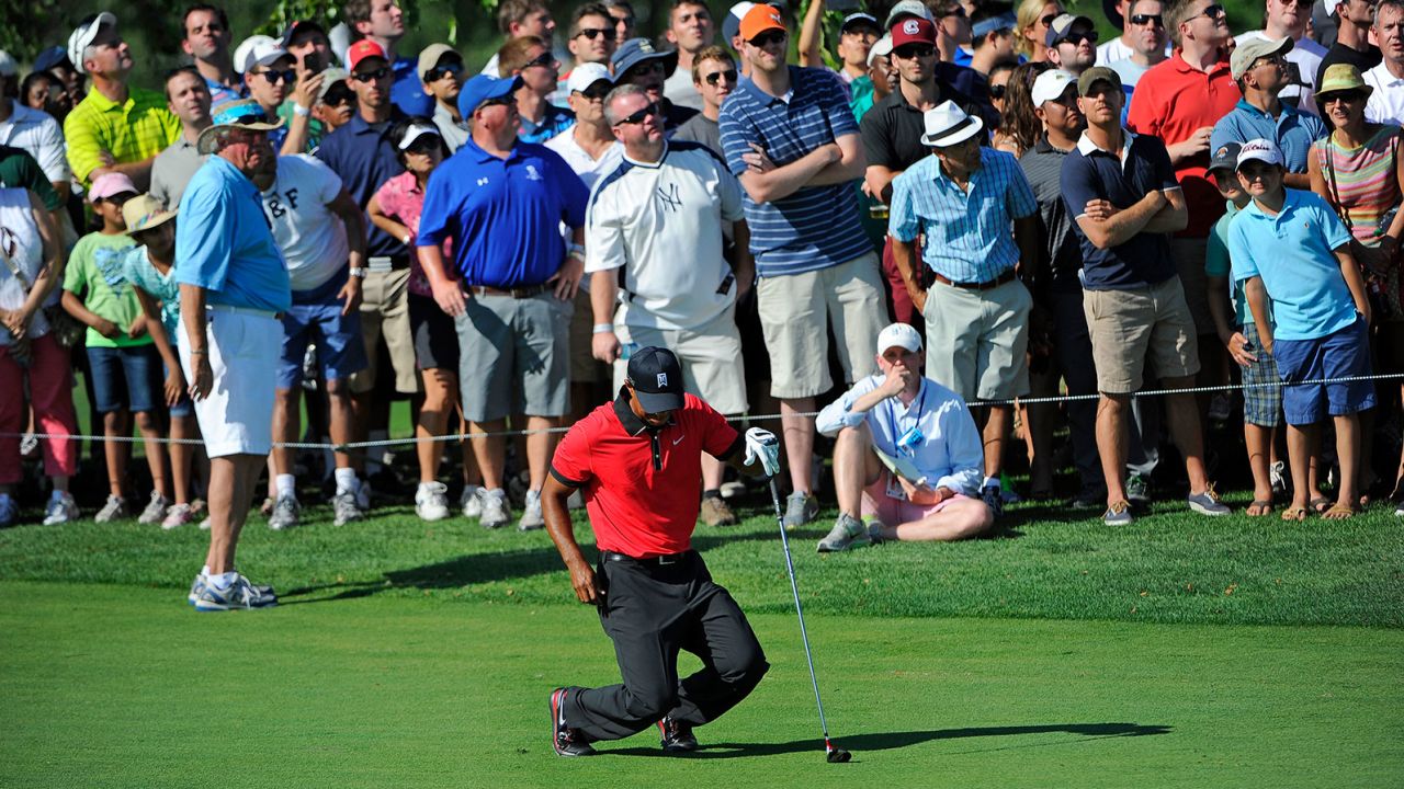 Woods falls to the ground in pain after hitting his second shot on the 13th hole during the final round of The Barclays at Liberty National Golf Club on August 25, 2013.