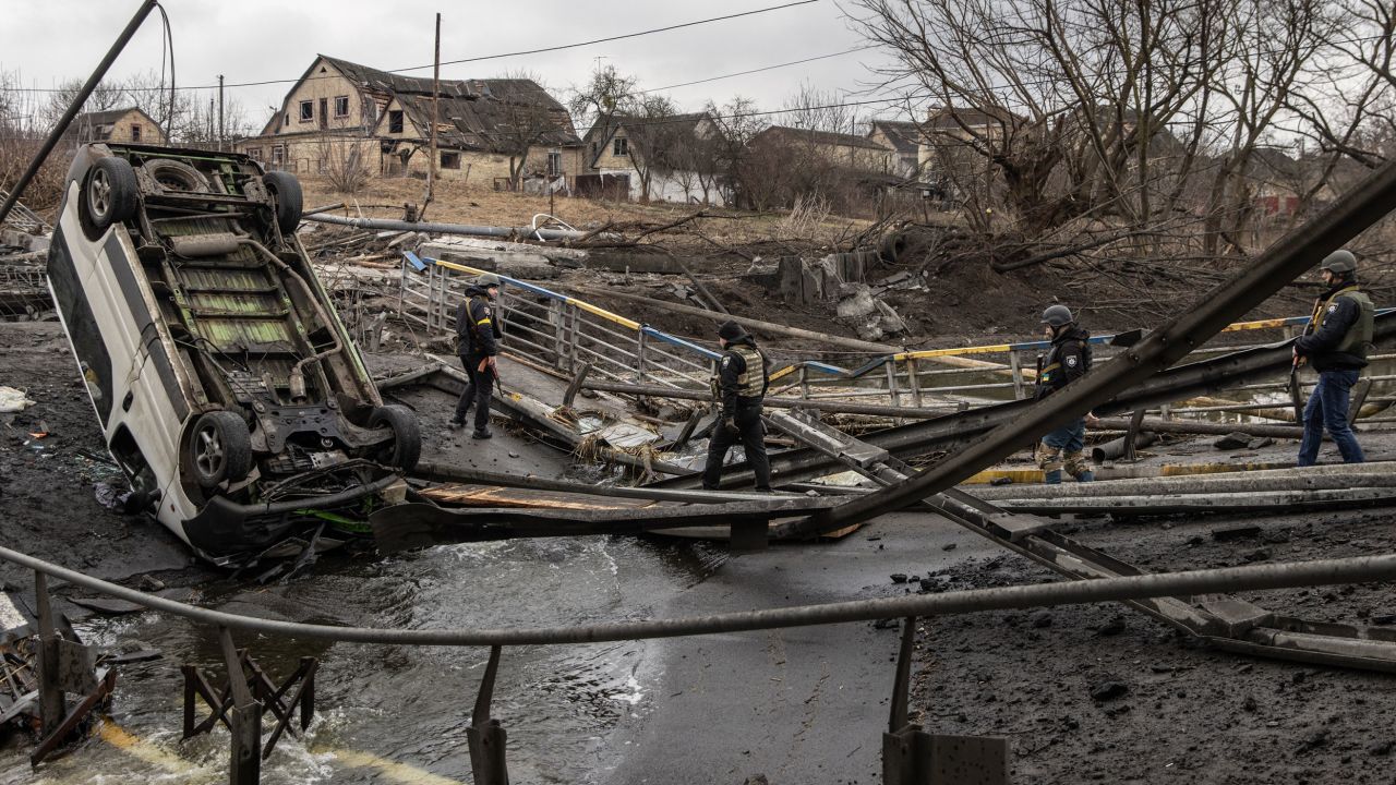Ukrainian military forces walk across a destroyed bridge in Irpin, Ukraine on Sunday. 