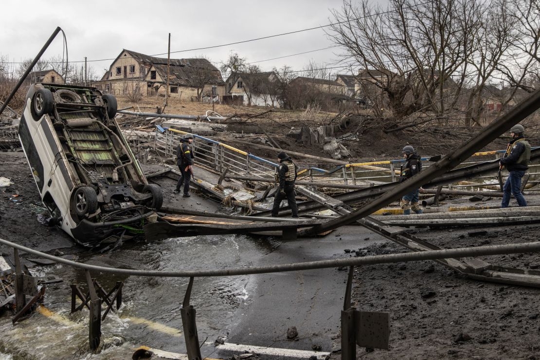 Ukrainian military forces walk across a destroyed bridge in Irpin, Ukraine on Sunday.