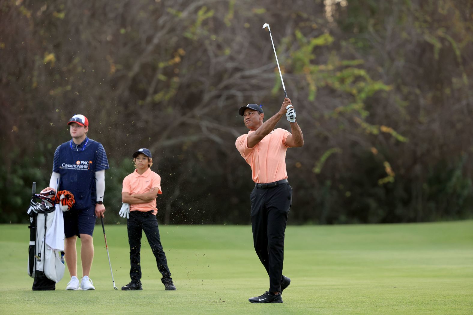 Woods plays a shot at the PNC Championship as his son, Charlie, watches in December 2021. It was Tiger's first time competing since the car crash, and he used a golf cart to get around the course. He and Charlie <a href="index.php?page=&url=https%3A%2F%2Fwww.cnn.com%2F2021%2F12%2F18%2Fsport%2Ftiger-woods-pnc-championship%2Findex.html" target="_blank">finished in second place.</a> "I'm a long way away from playing tournament golf," Tiger said. "This is hit, hop in a cart."