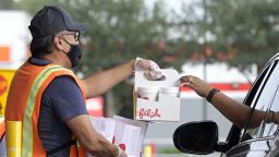 An employee wears a face mask to help curb the spread of COVID-19 while handing out food orders outside a drive-thru window of a Chick-fil-A restaurant during the coronavirus pandemic, on Thursday, Nov. 4, 2021, in Orlando, Florida.