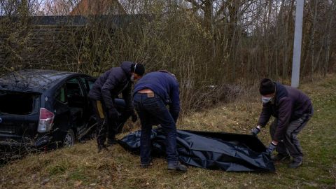 Volunteers collect the body of a man who was shot while driving his car in Borodianka, Ukraine.