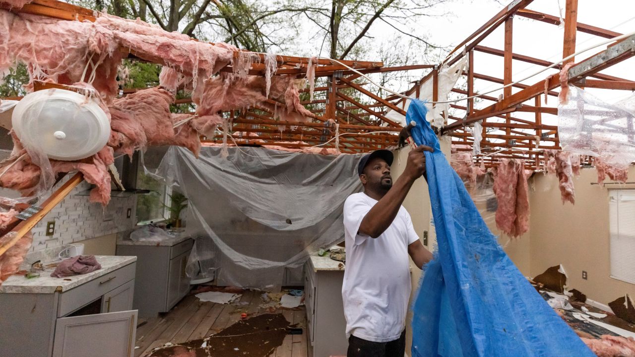 Khary Johnson places tarps on the roof of a damaged home after a tornado passed through an area in Allendale, South Carolina, on Tuesday. 