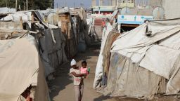 A girl carries a child as she walks through a makeshift camp for internally displaced people (IDPs) in Aden, Yemen. 