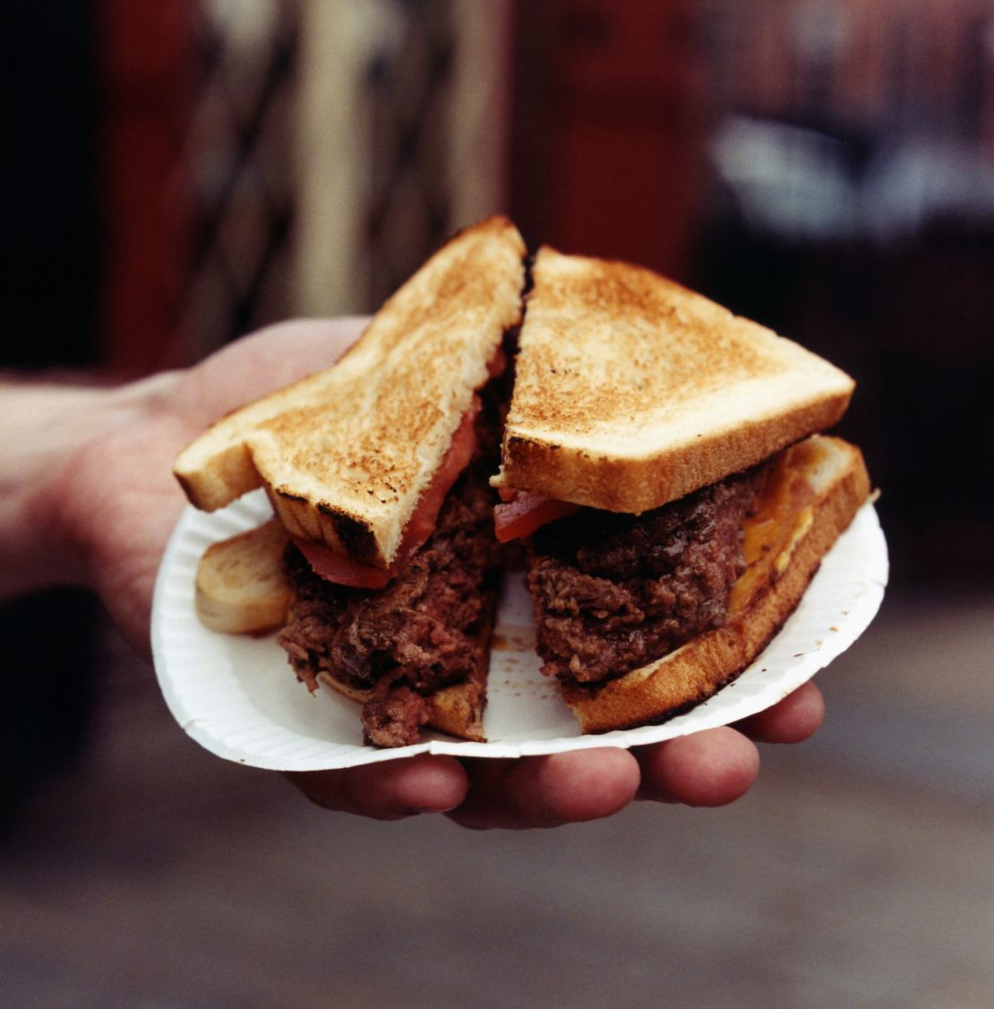 Hamburger served at Louis' Lunch in New Haven, Connecticut, with tomato, cheese onions on white bread.