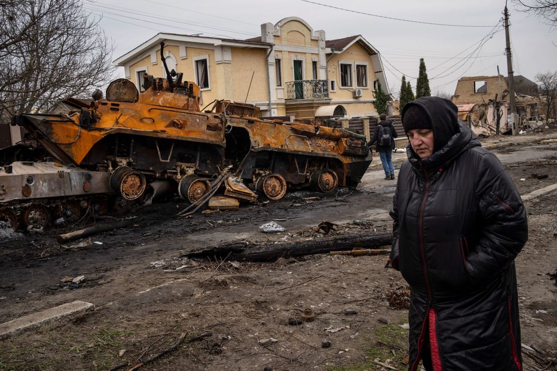 A woman walks next to a destroyed Russian armor vehicle in Bucha on April 5.