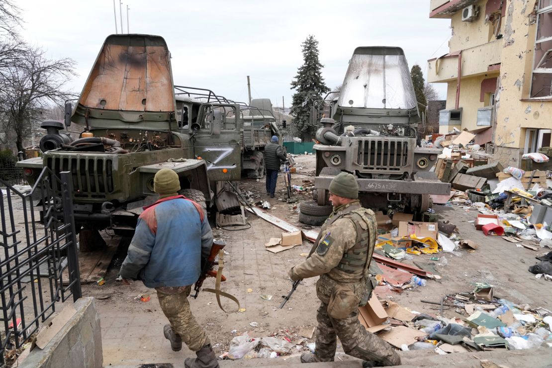 Ukrainian soldiers in front of damaged Russian military trucks in the town of Trostsyanets, some 400 kilometers (250 miles) east of Kyiv on March 28.